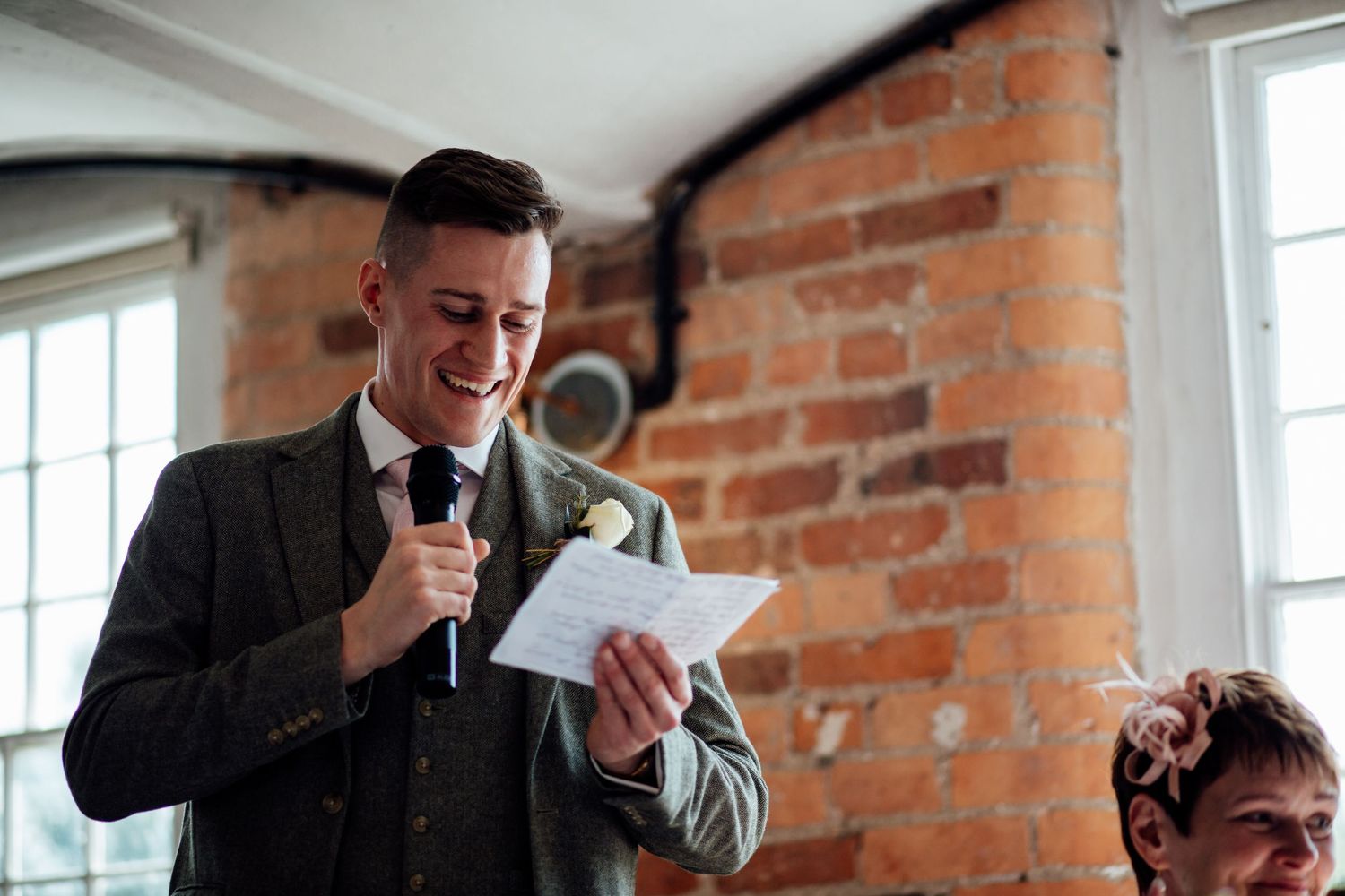 Wedding reception in a rustic brick-walled venue with exposed beams.