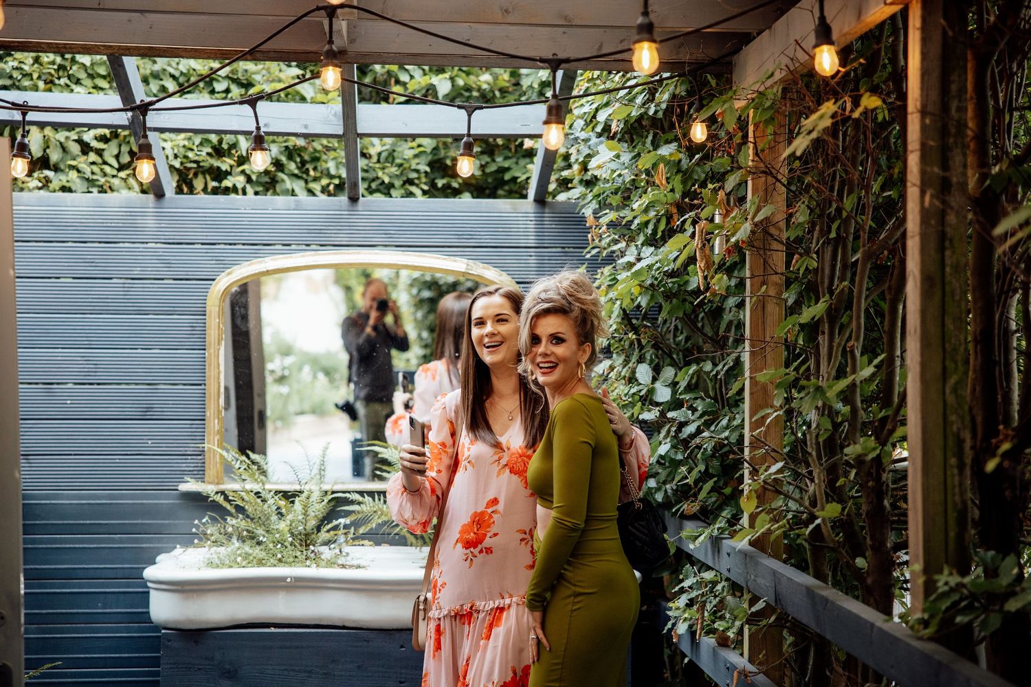 Outdoor wedding reception setup with string lights and greenery decorations.