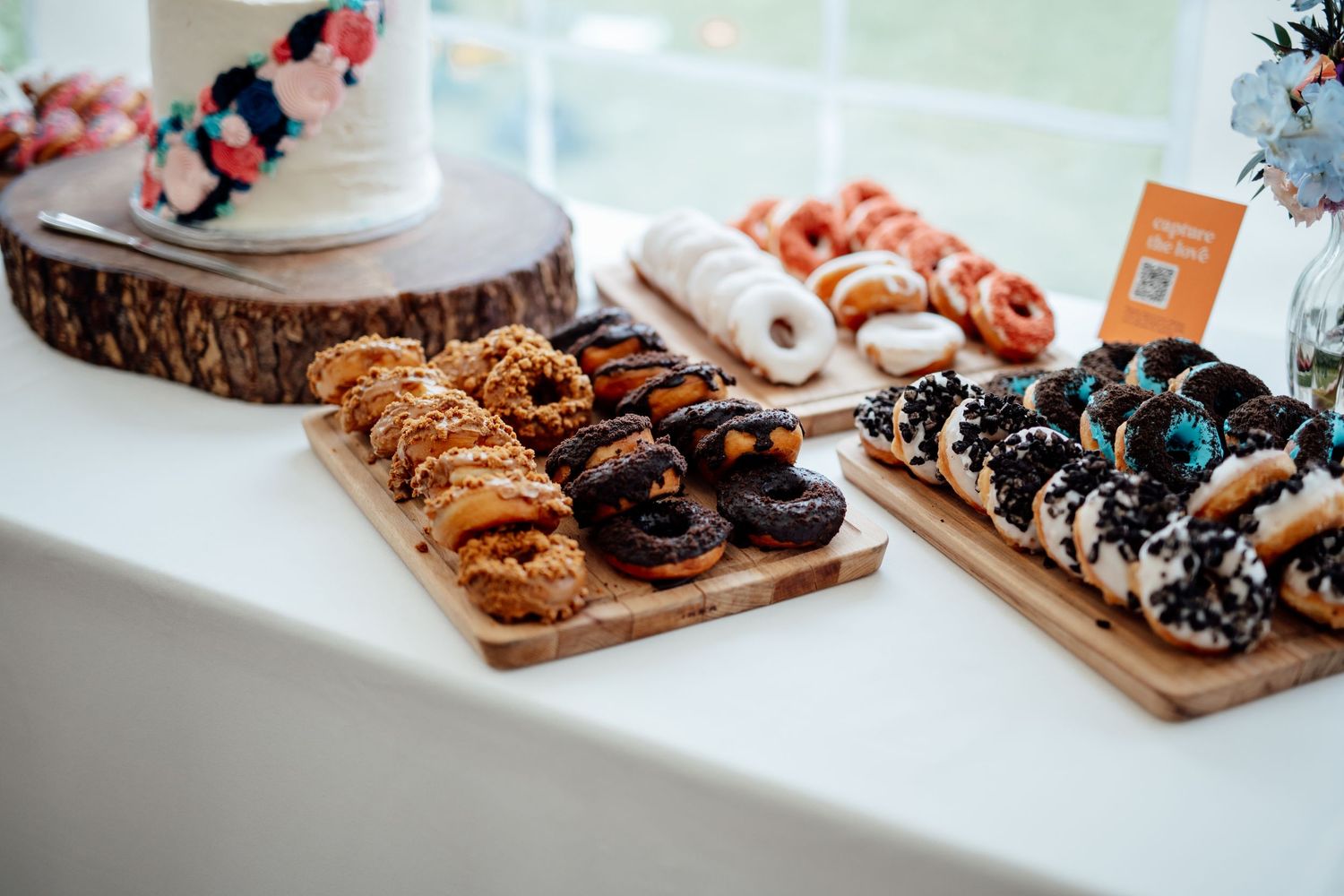Assorted donuts and desserts displayed on wooden boards at wedding reception.