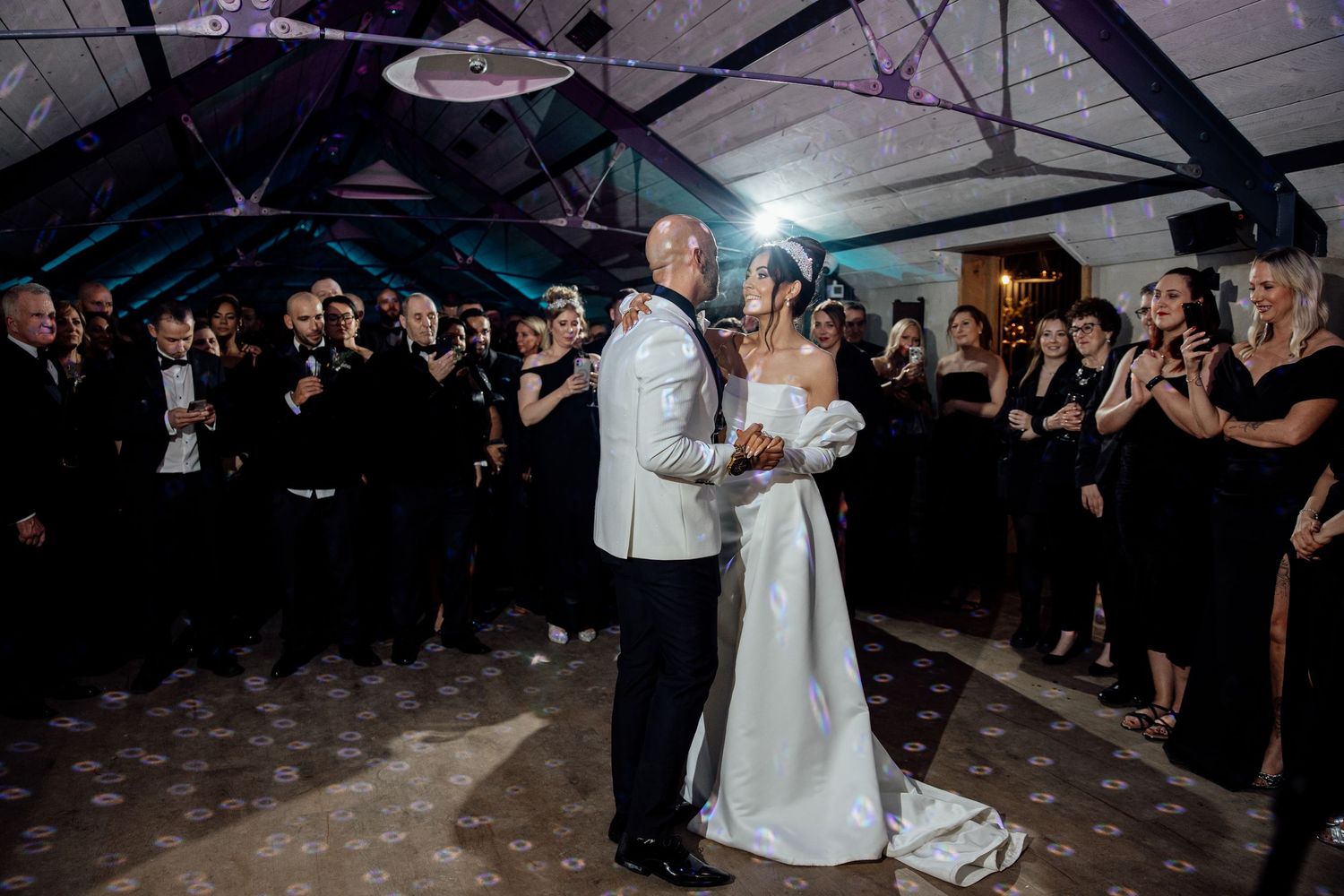 Wedding reception dance with guests surrounding the couple in a modern industrial venue.