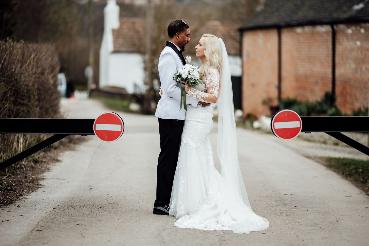 Bride and groom share a romantic moment on a path flanked by red stop signs on their wedding day.