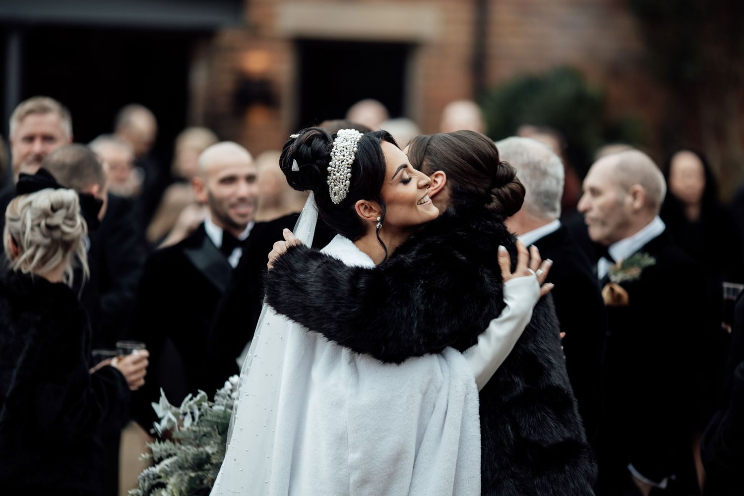 Wedding guests gather outdoors in formal attire watching a celebratory moment.