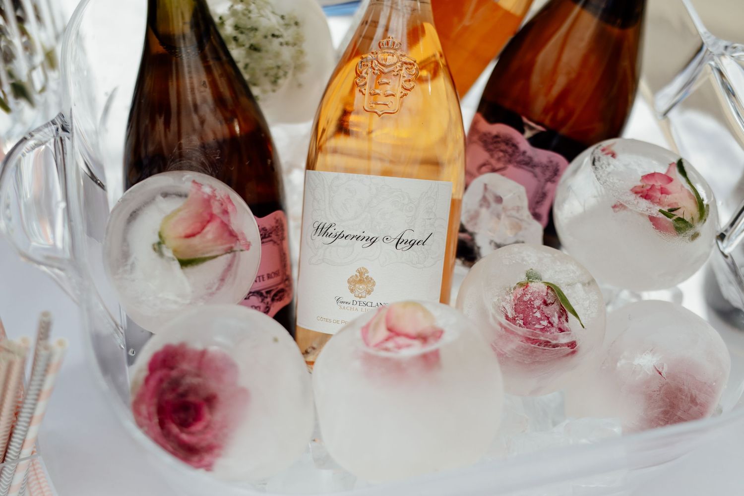 Elegant wedding reception table setting with champagne bottles and rose petal decorations.