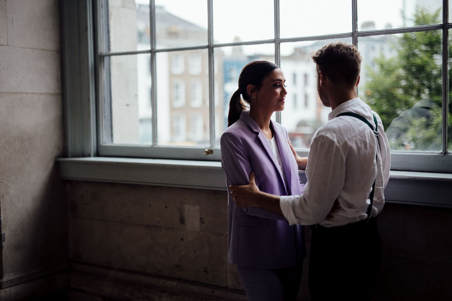 Intimate moment captured in natural window light of an industrial building interior.