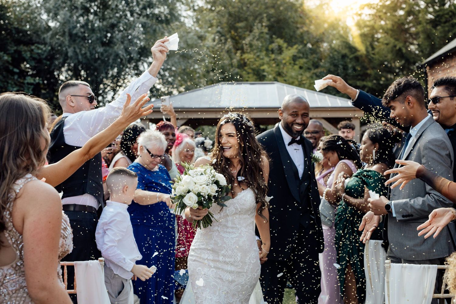Guests shower the newlyweds with confetti during an outdoor wedding celebration.