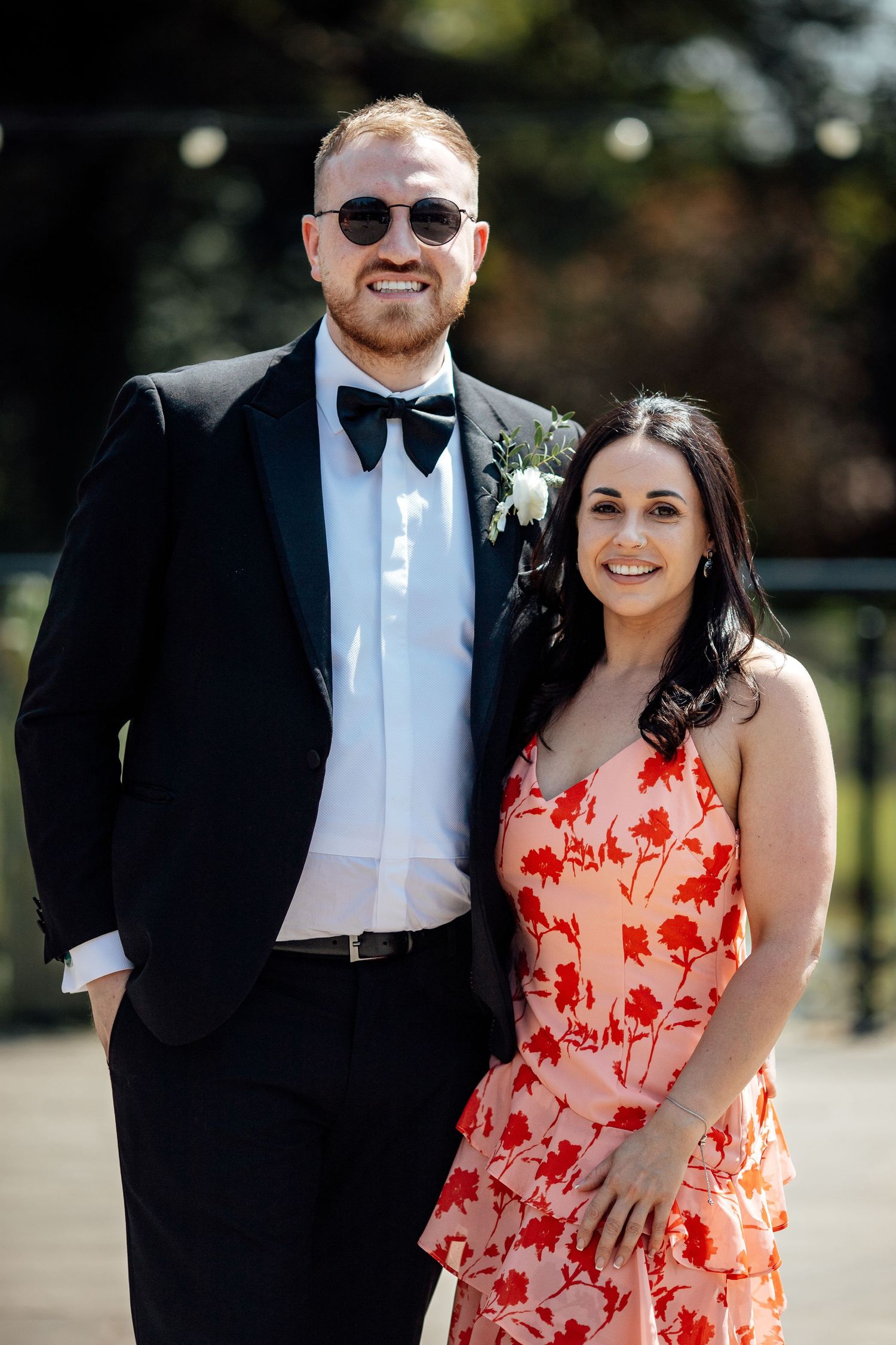 Wedding party members posing outdoors on a sunny day in formal attire.