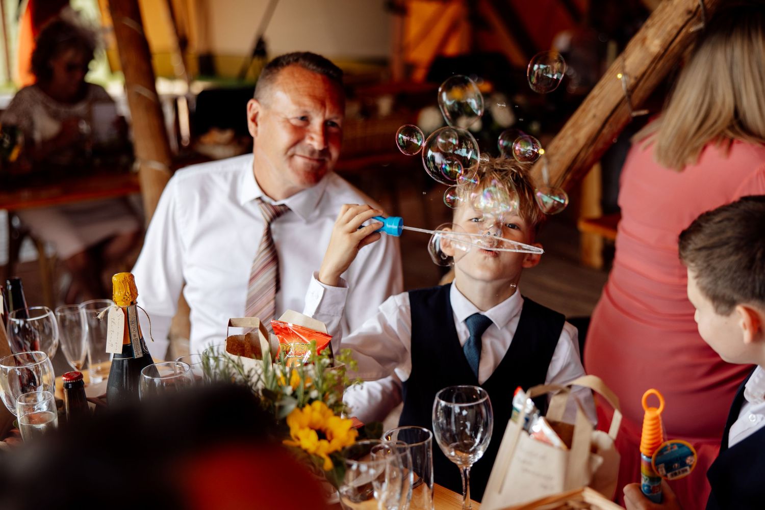 Wedding reception guests enjoy dinner and conversation at decorated table.