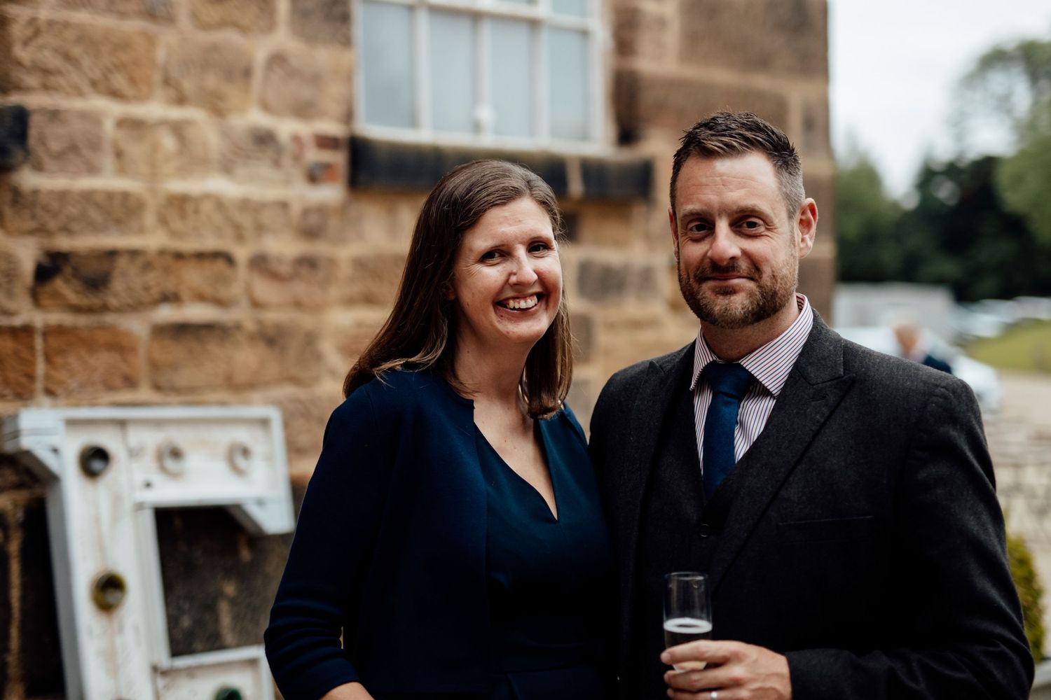 Joyful outdoor wedding moments captured against stone building backdrop.