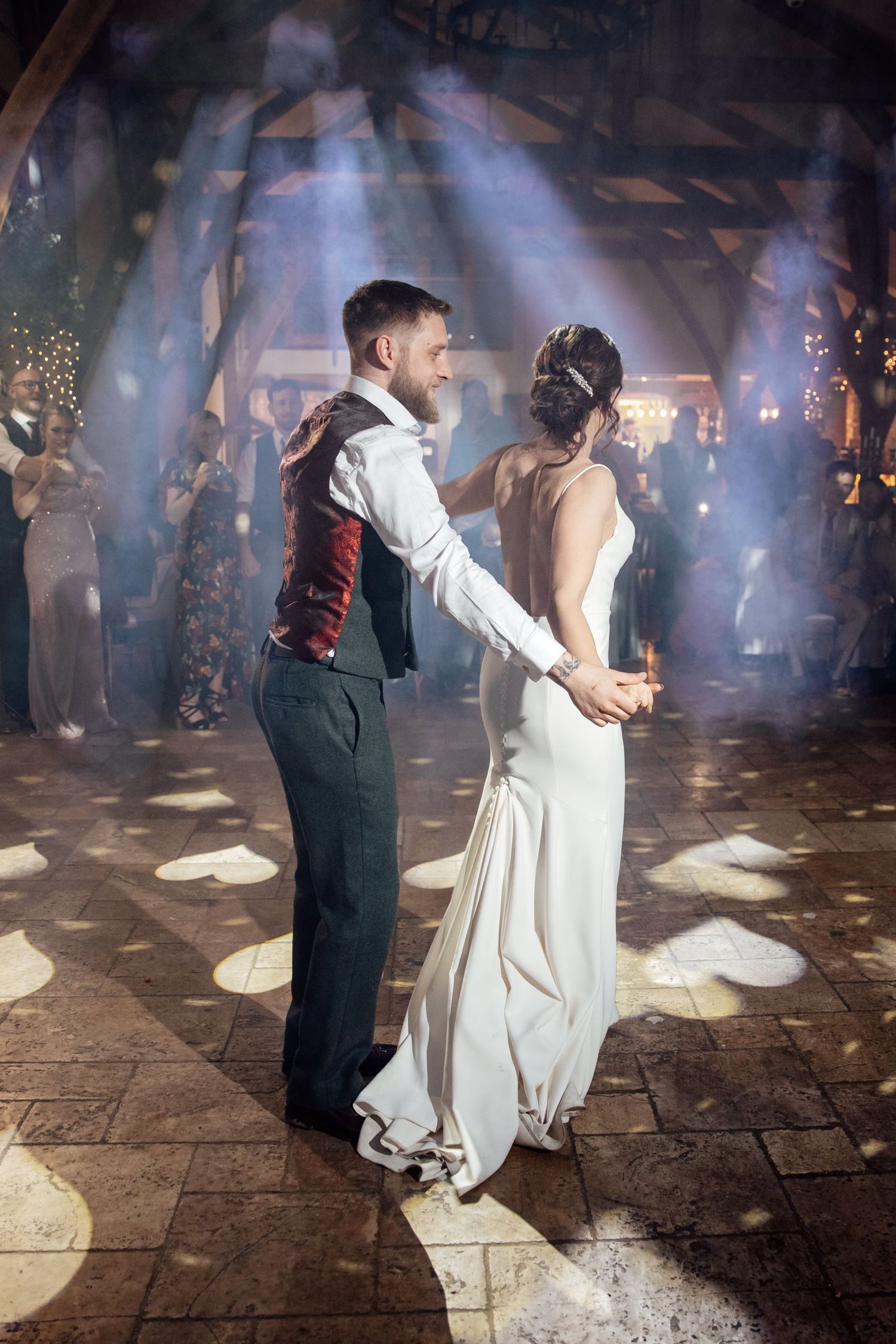 Couple dancing in a smoky atmosphere with dramatic lighting at their wedding reception.