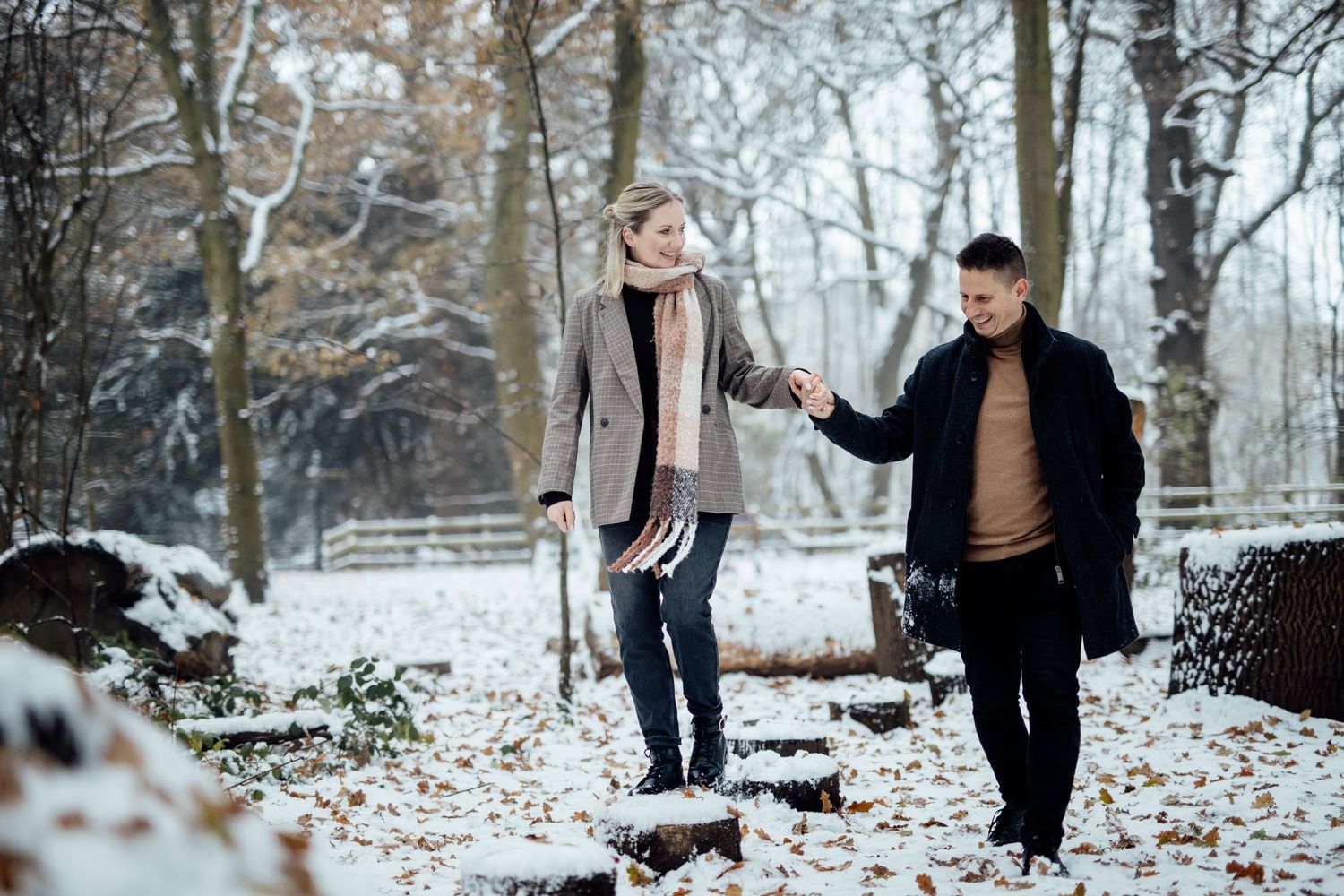 Couple playfully interacting in a snowy winter forest setting.