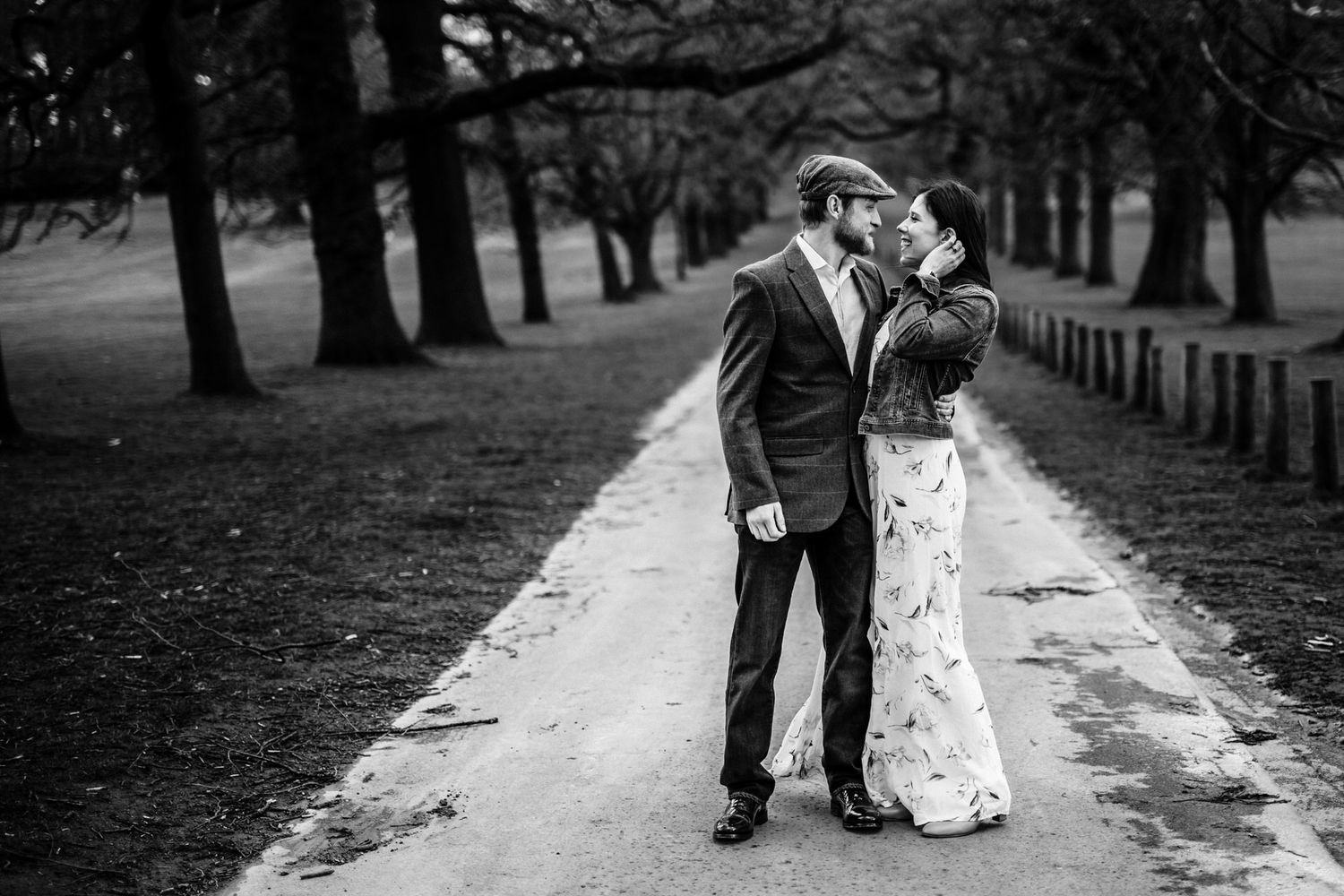 A couple walks together on a winding path through a park with bare trees.
