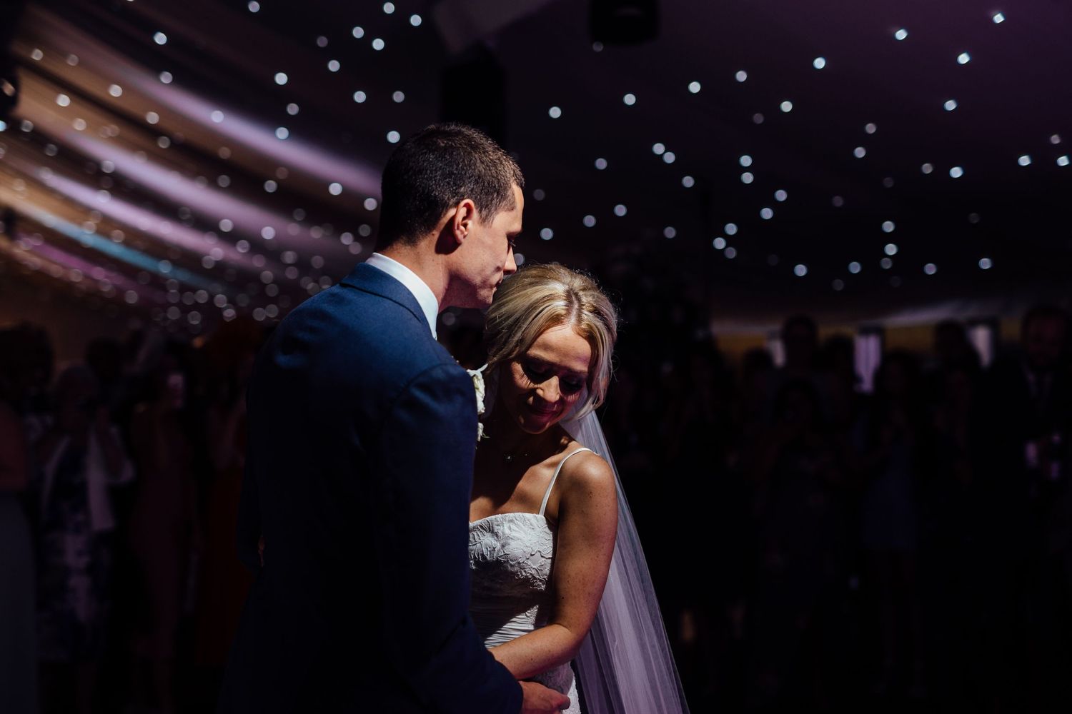 Couples share their first dance under twinkling lights at evening reception.