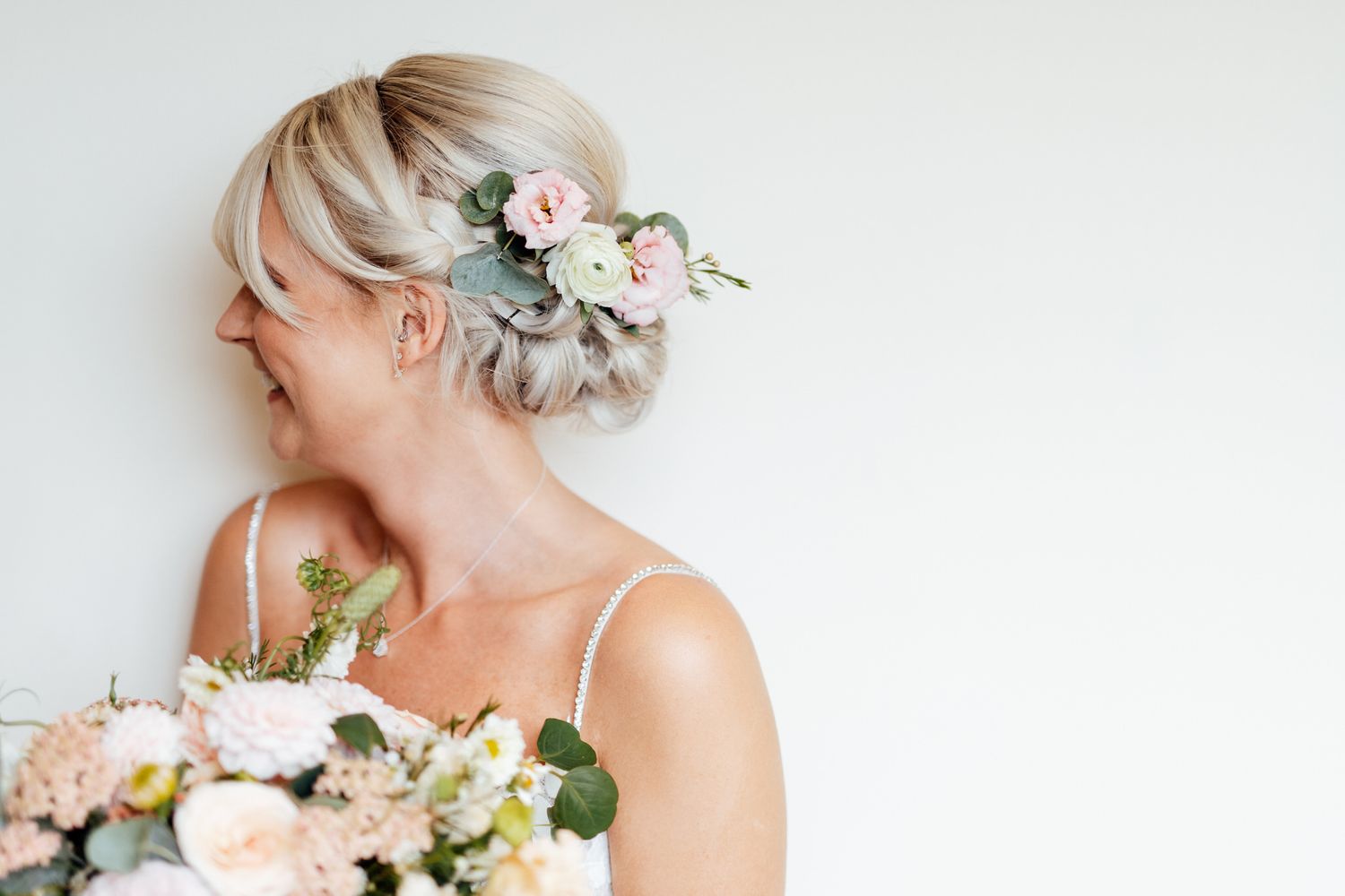 Elegant bridal details featuring soft pink flowers and delicate hair accessories against white background.