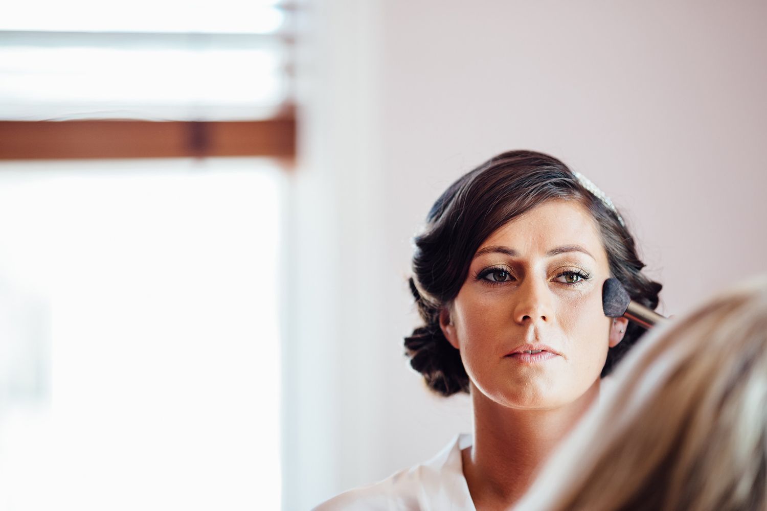 Getting ready scene in an elegant white room with soft natural window light.