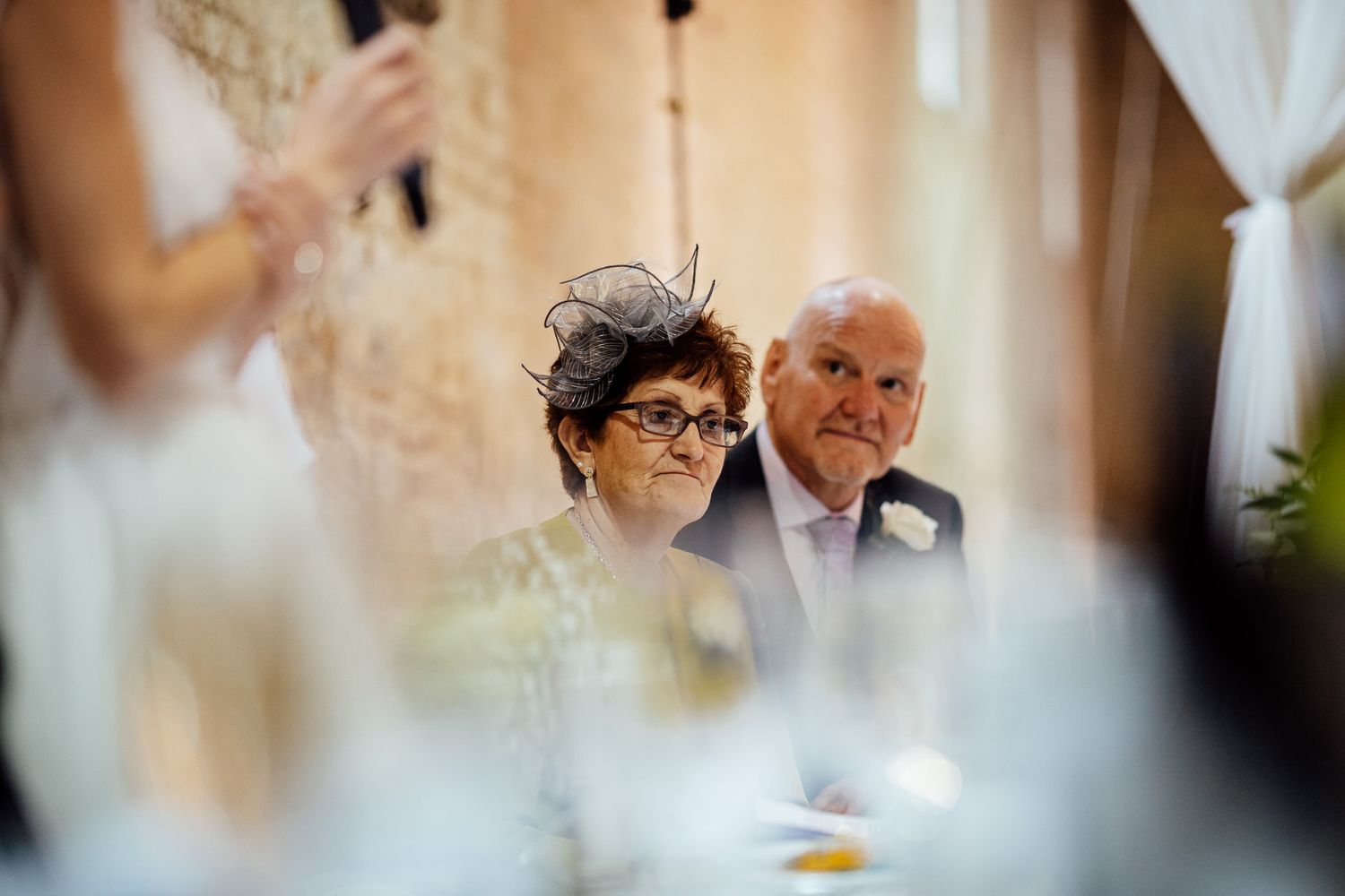 Wedding guests enjoying an elegant reception with string lights and brick walls in the background.
