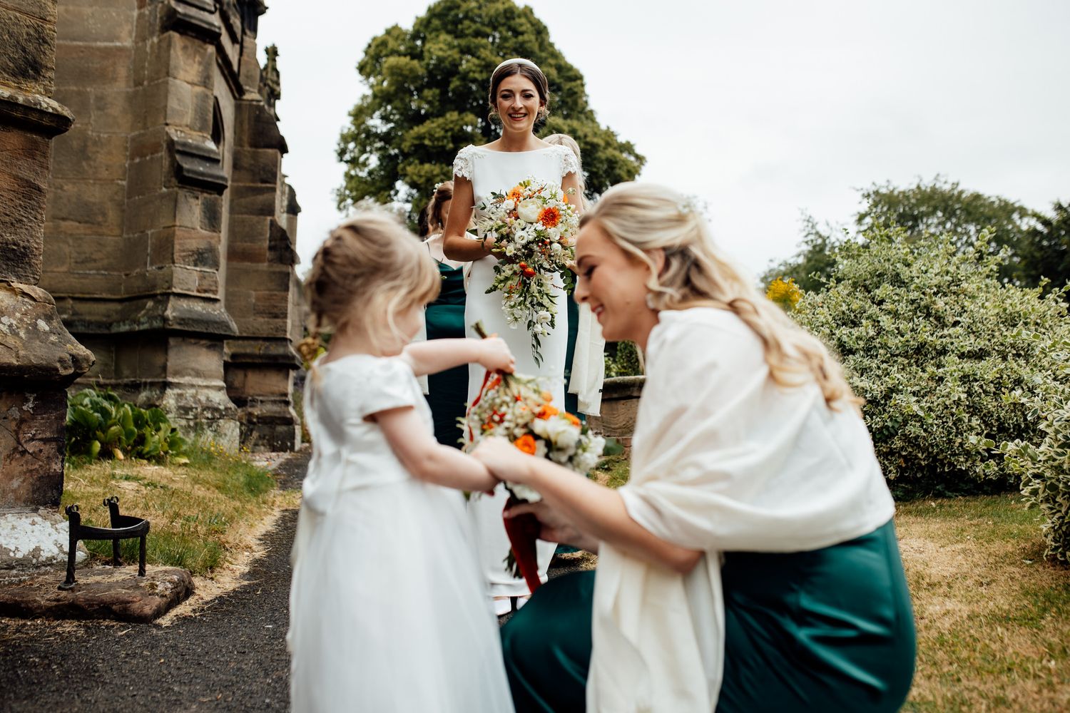 Wedding party members enjoying candid moments on church grounds.