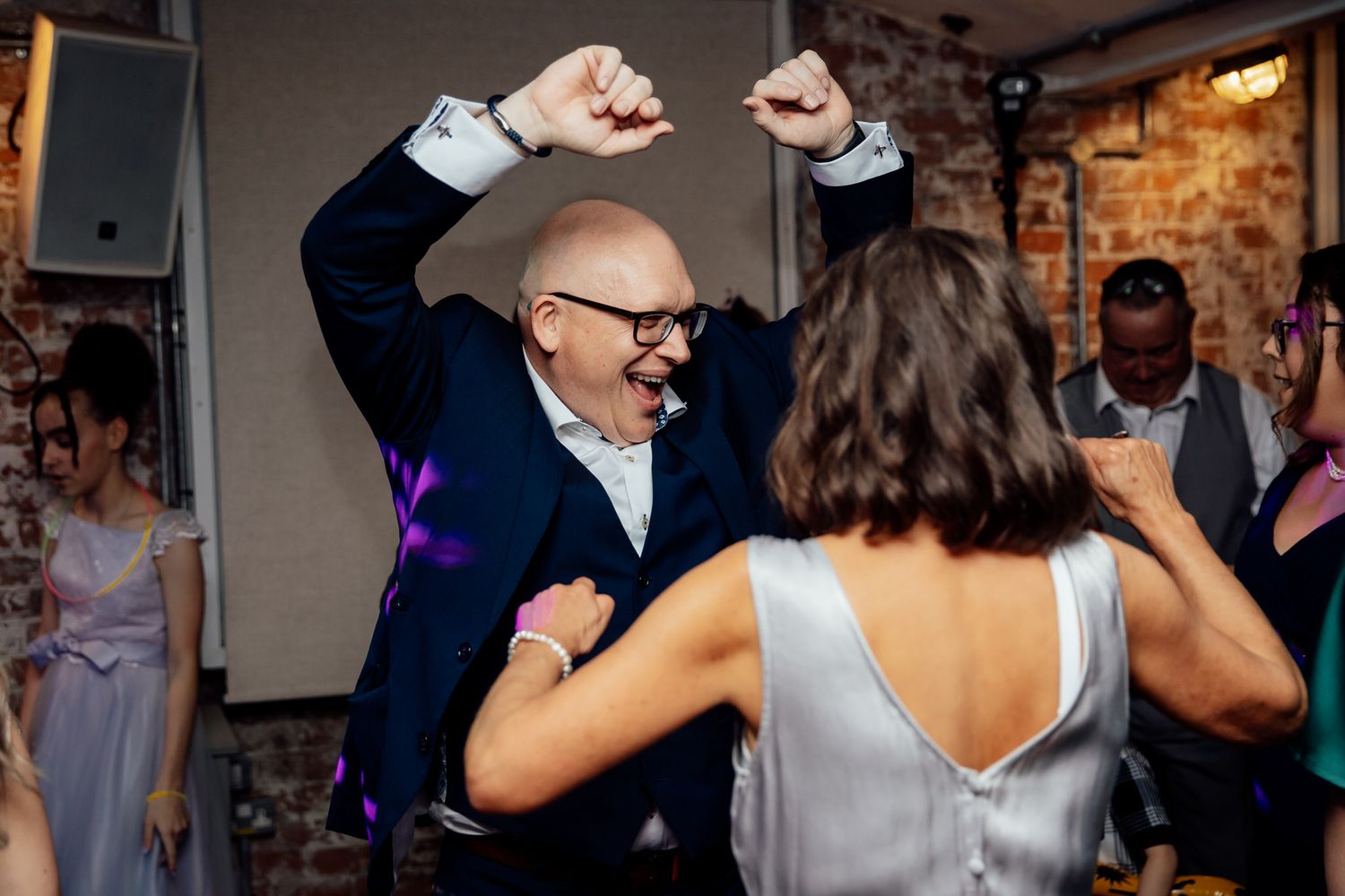 Wedding guests dancing and celebrating at a lively reception party.