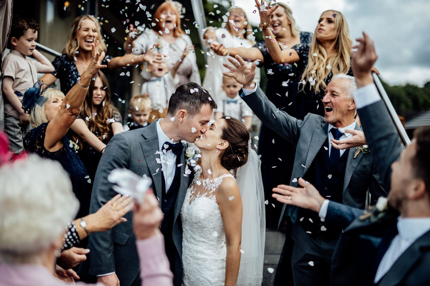 Wedding guests celebrate with confetti during an outdoor ceremony.