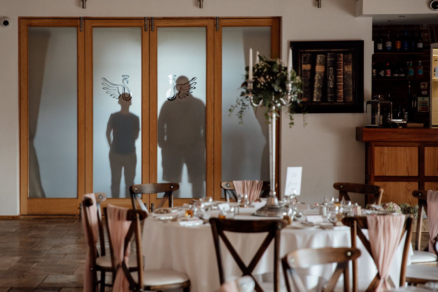 Elegant wedding reception venue with wooden chairs and tables set for dining.