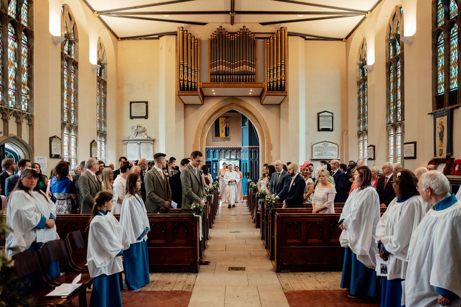 Interior of a church with white-robed choir members lined up in wooden pews.