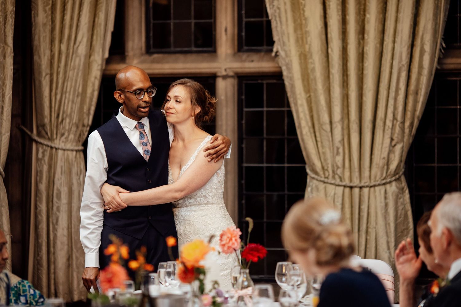 Romantic moment during wedding reception with elegant drapes and chandelier.