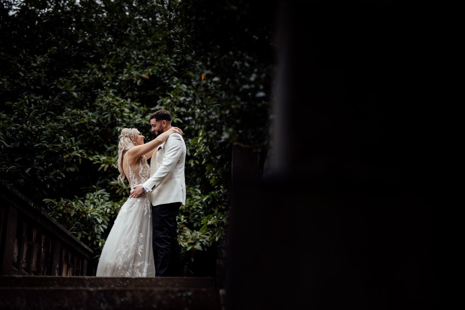A romantic wedding couple embraces under dim lighting during their reception.