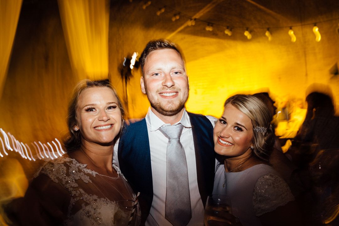 Wedding reception party with warm amber lighting and guests mingling.