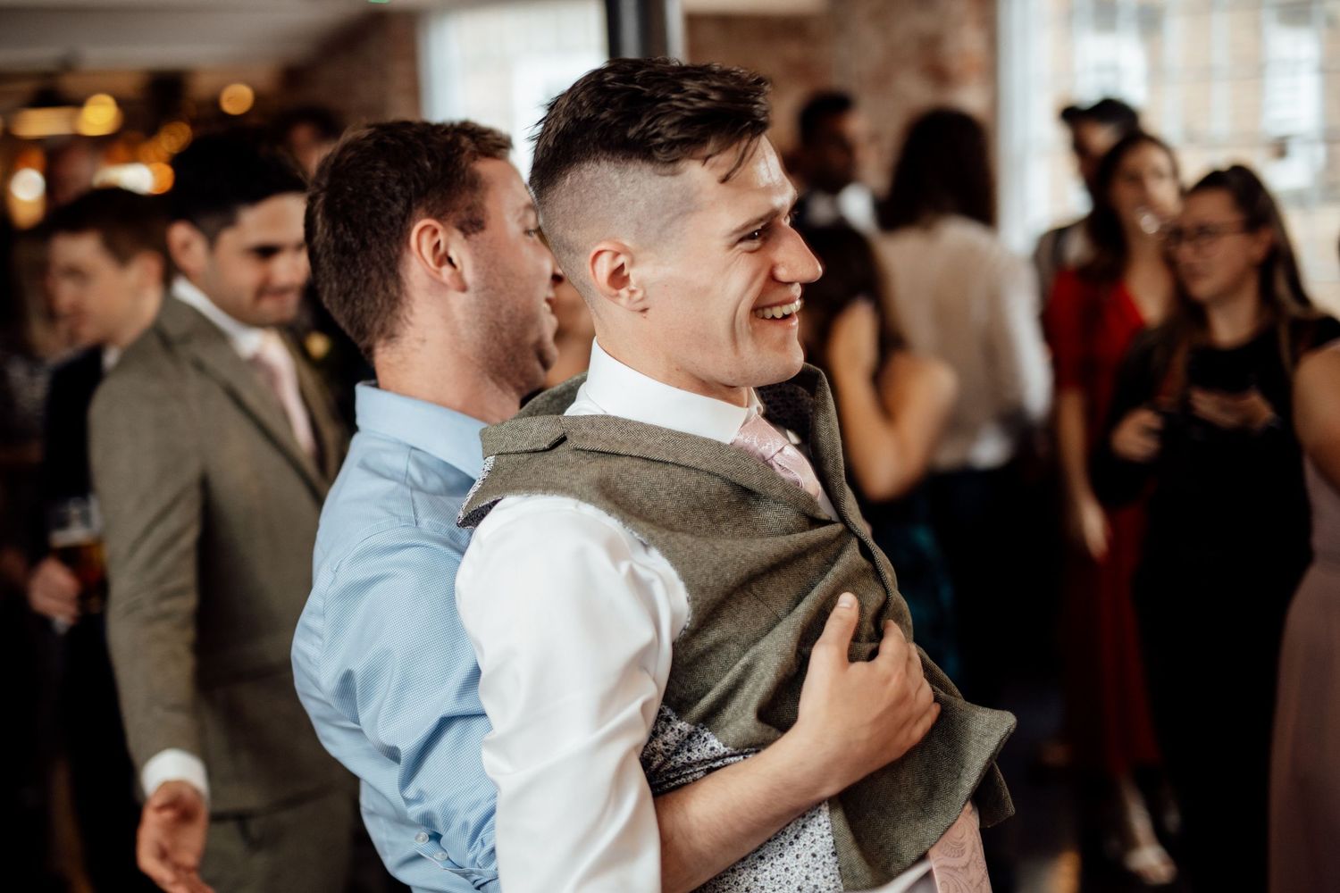 Wedding reception guests dancing and celebrating on a crowded dance floor.