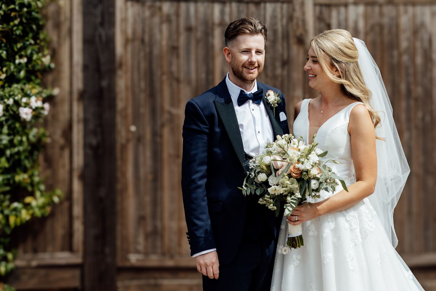 Romantic wedding couple portraits against wooden fence backdrop.
