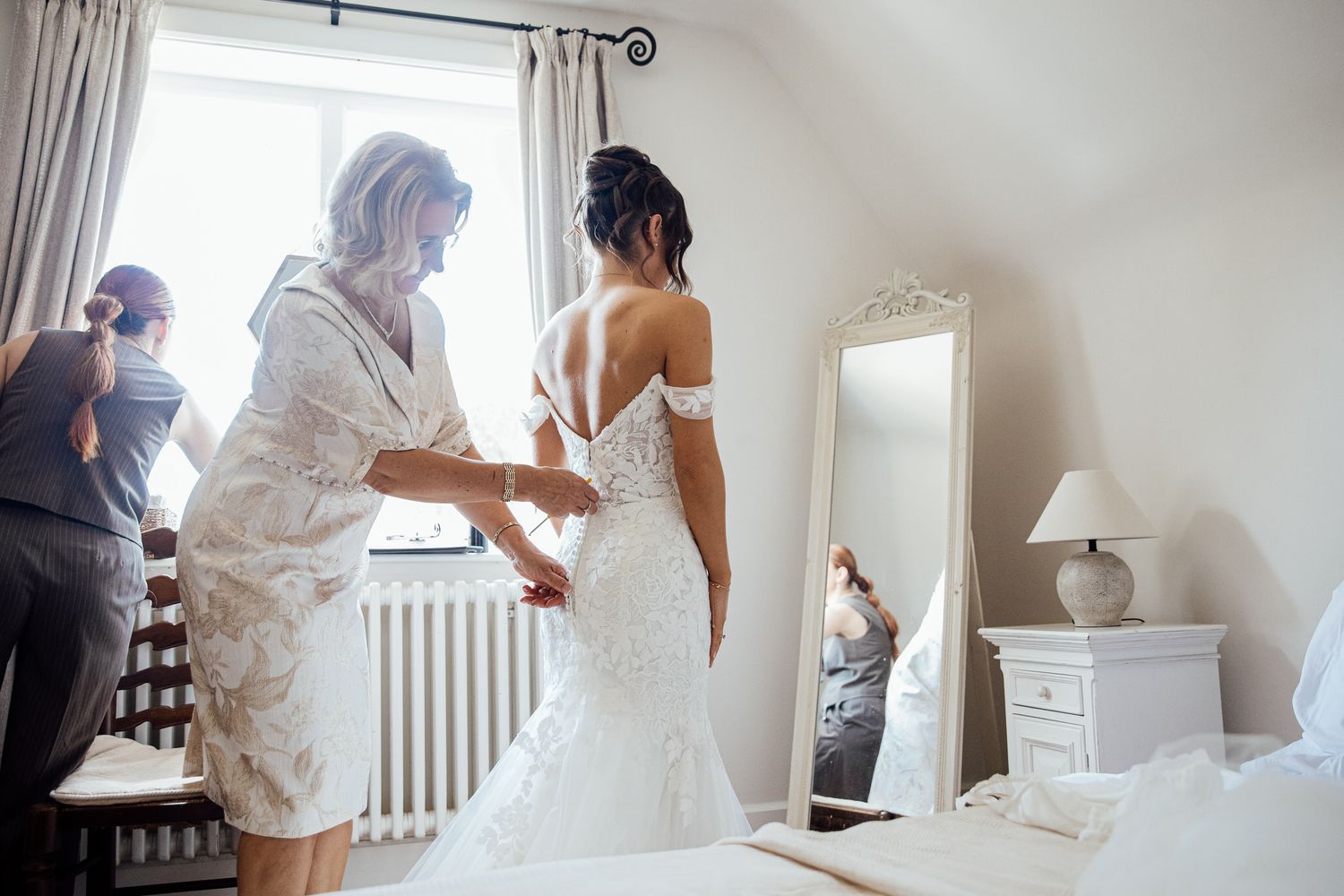 Getting ready scene with white robes and natural window light in a bridal suite.
