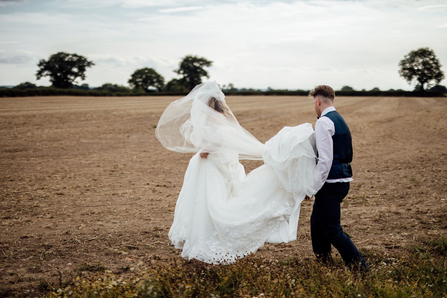 White wedding dress billows dramatically across an open field.
