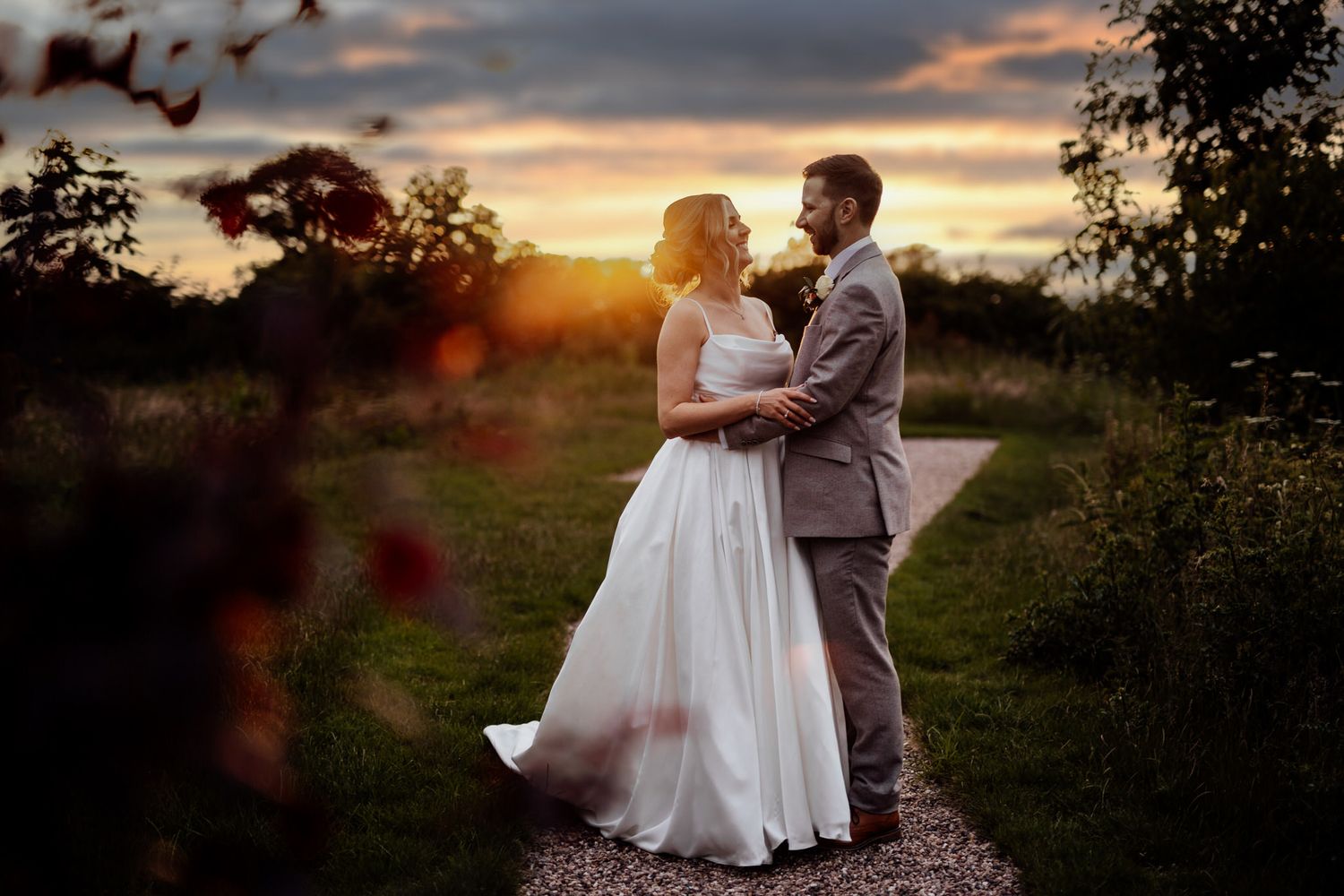 Couple sharing romantic moments at sunset in an outdoor wedding setting.