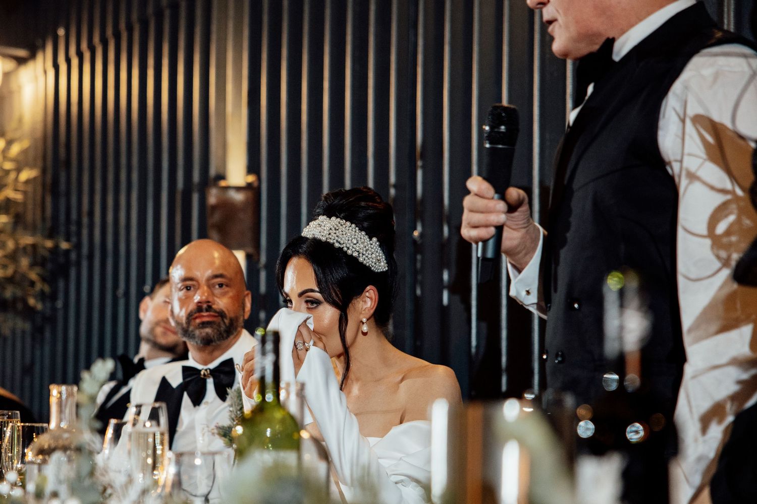 Wedding reception dinner scene with elegant table settings and formal attire.