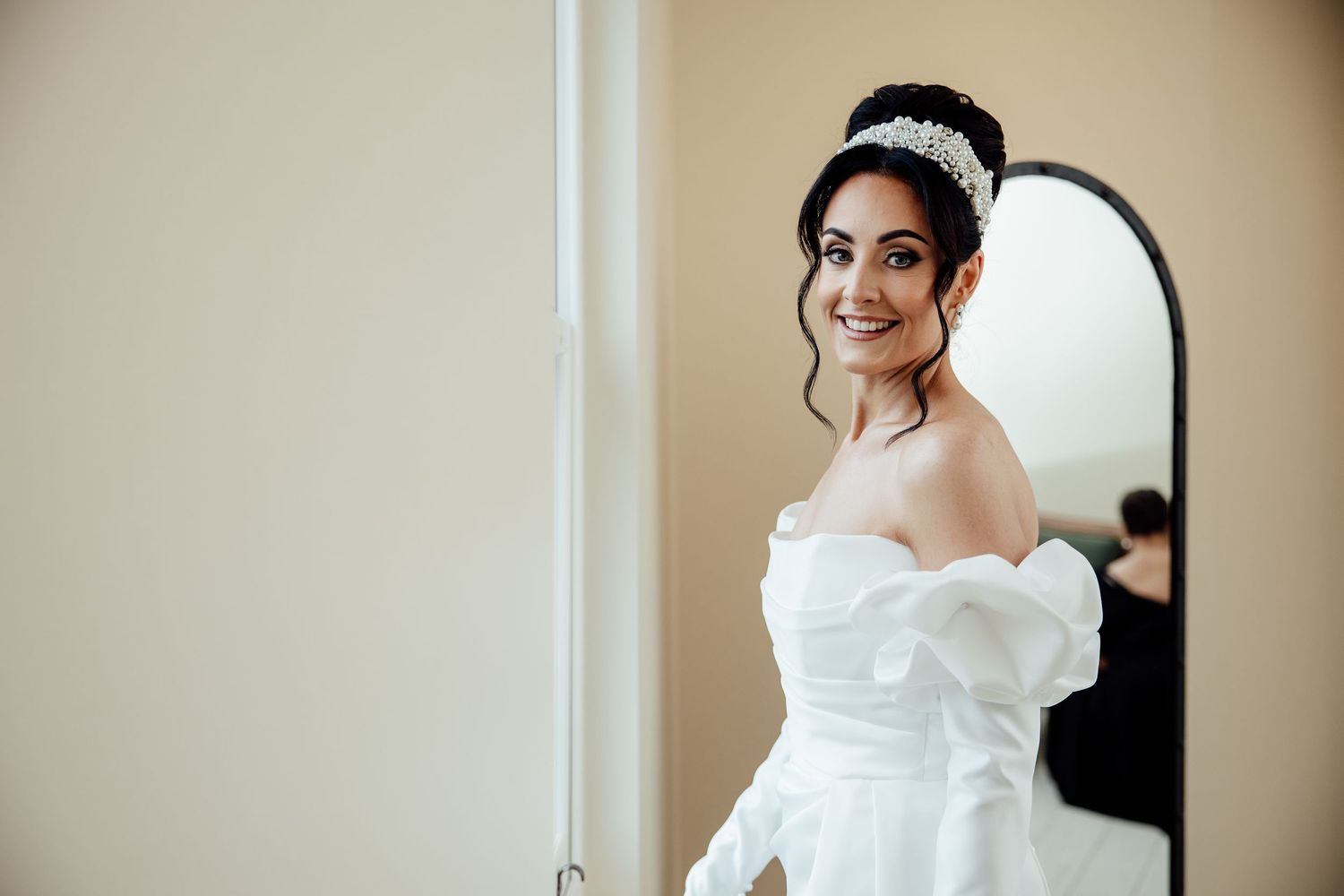 Bride getting ready in elegant white wedding dress near window.