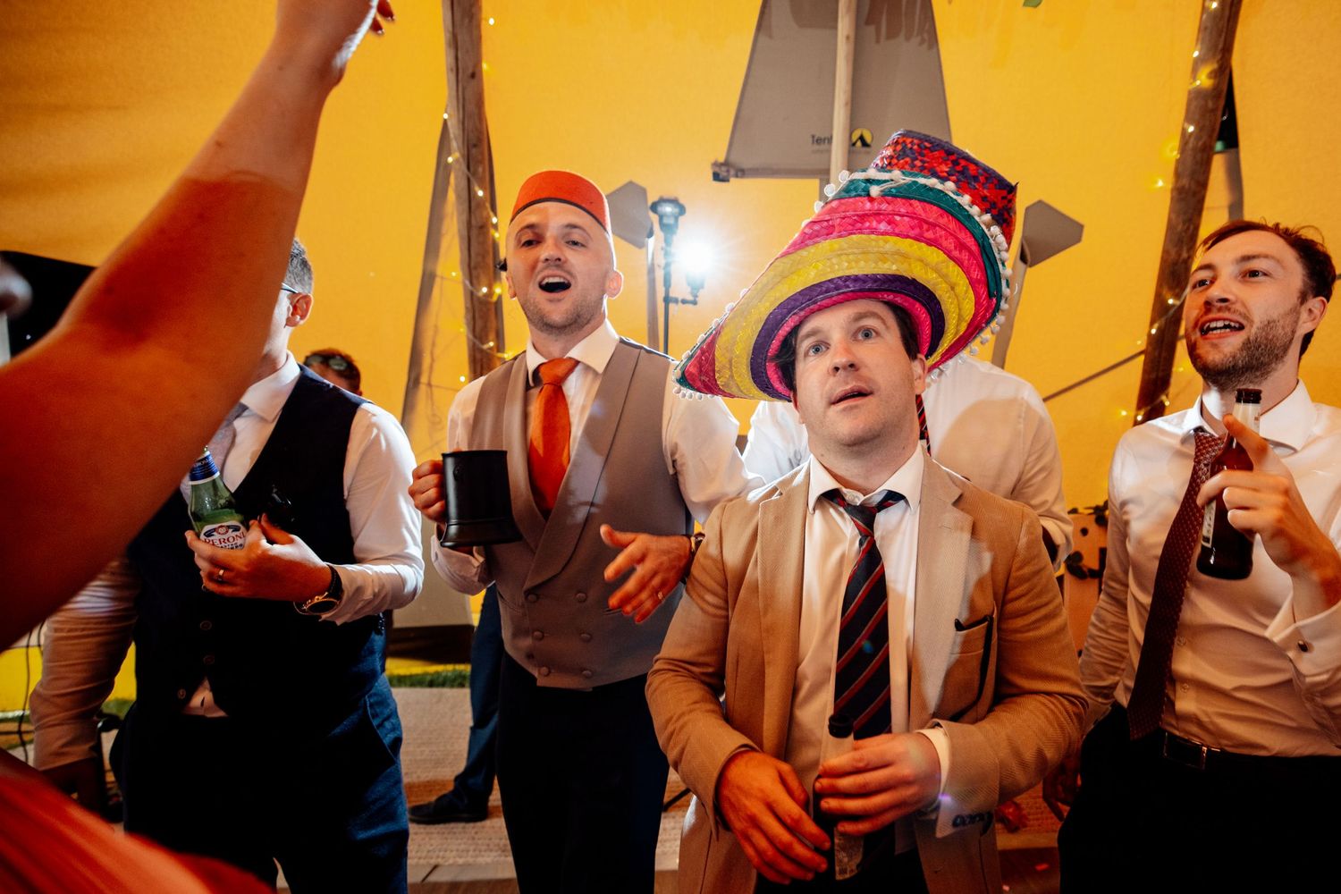 Wedding guests celebrate and dance together at a lively indoor reception party.