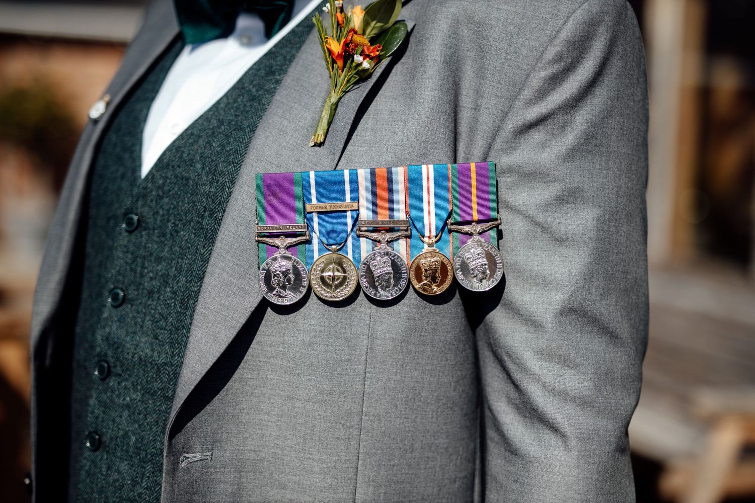 Military medals and service ribbons displayed on formal grey suit jacket.
