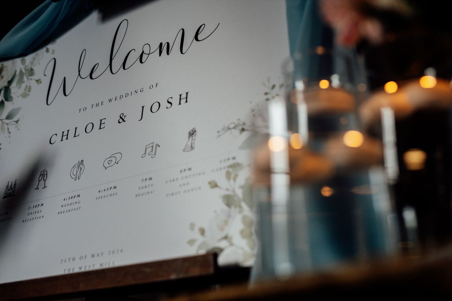 Wedding welcome sign with candlelight and floral decorations.