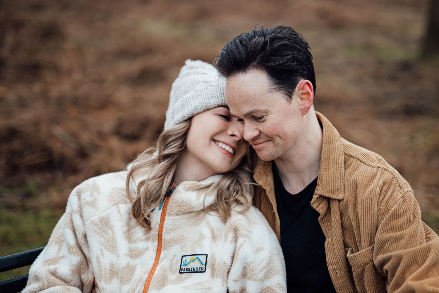 Romantic couple sharing intimate moments outdoors in winter clothing during a casual photoshoot.