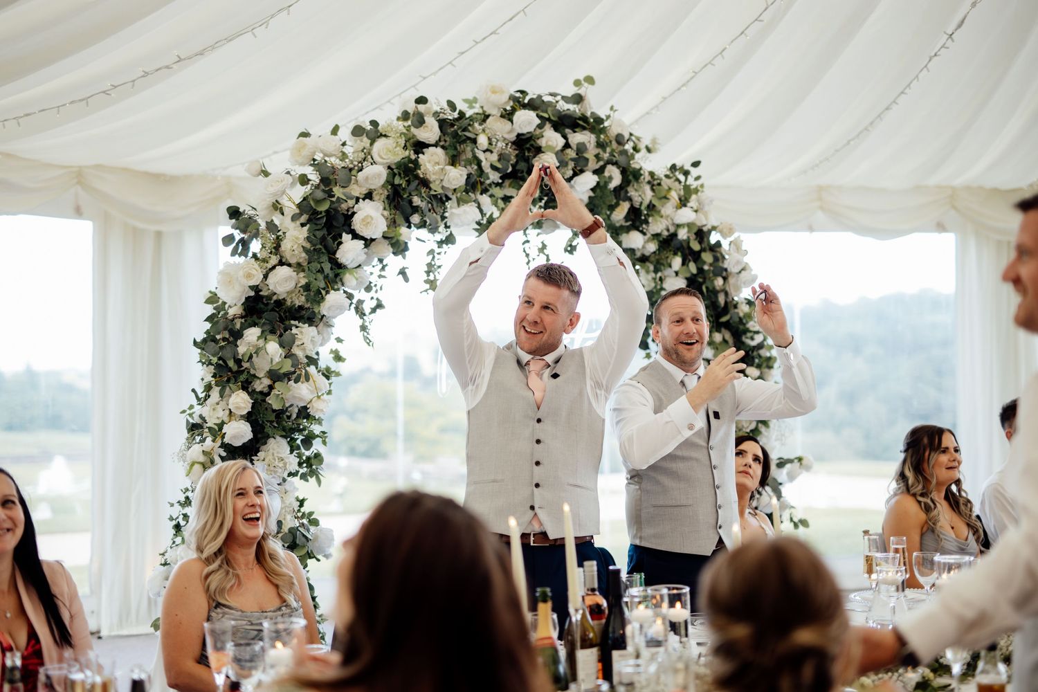 Wedding reception venue decorated with elegant white draping and floral arrangements.