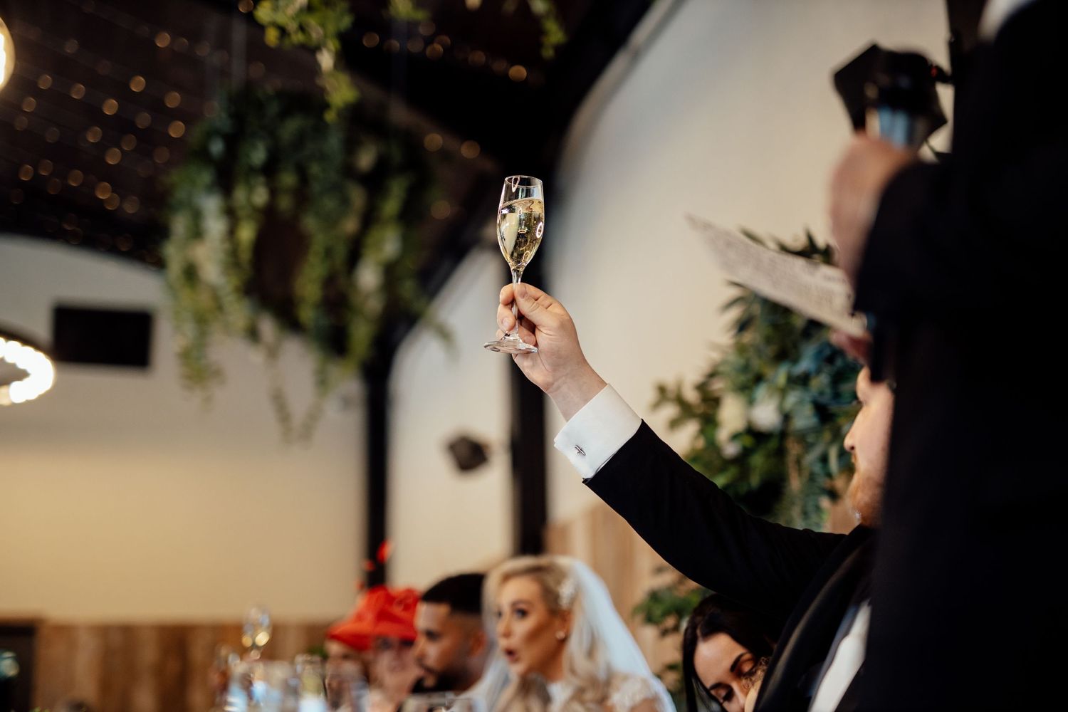 Wedding celebration at an indoor venue with guests dancing and toasting.