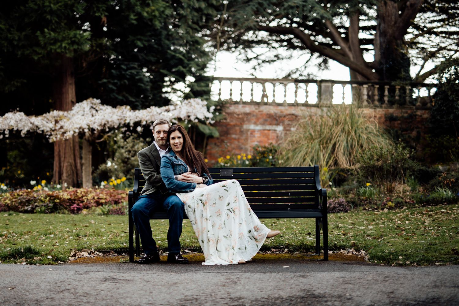 A couple shares romantic moments on park benches surrounded by autumn scenery.