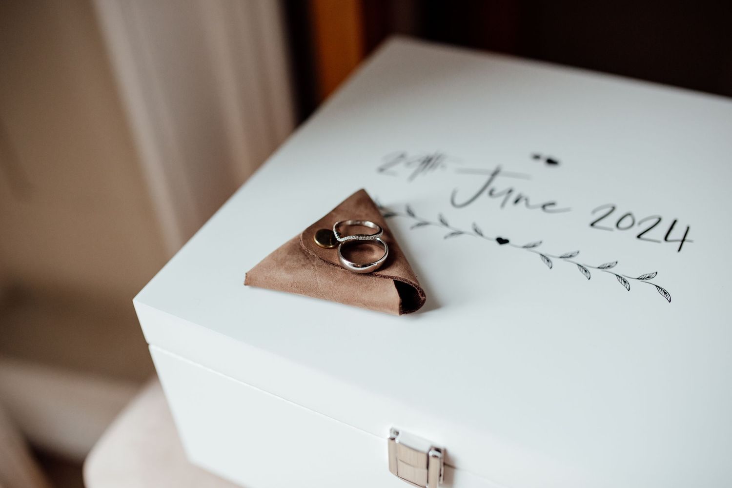 Wedding rings and details displayed on white paper with elegant calligraphy.