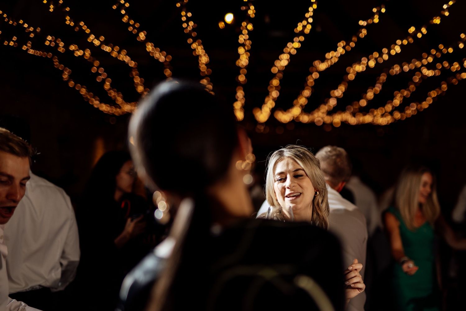 Wedding reception dance floor illuminated by overhead string lights creating a magical atmosphere.