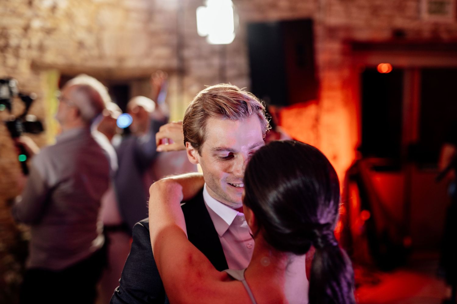 Couples dancing at dimly lit wedding reception party.
