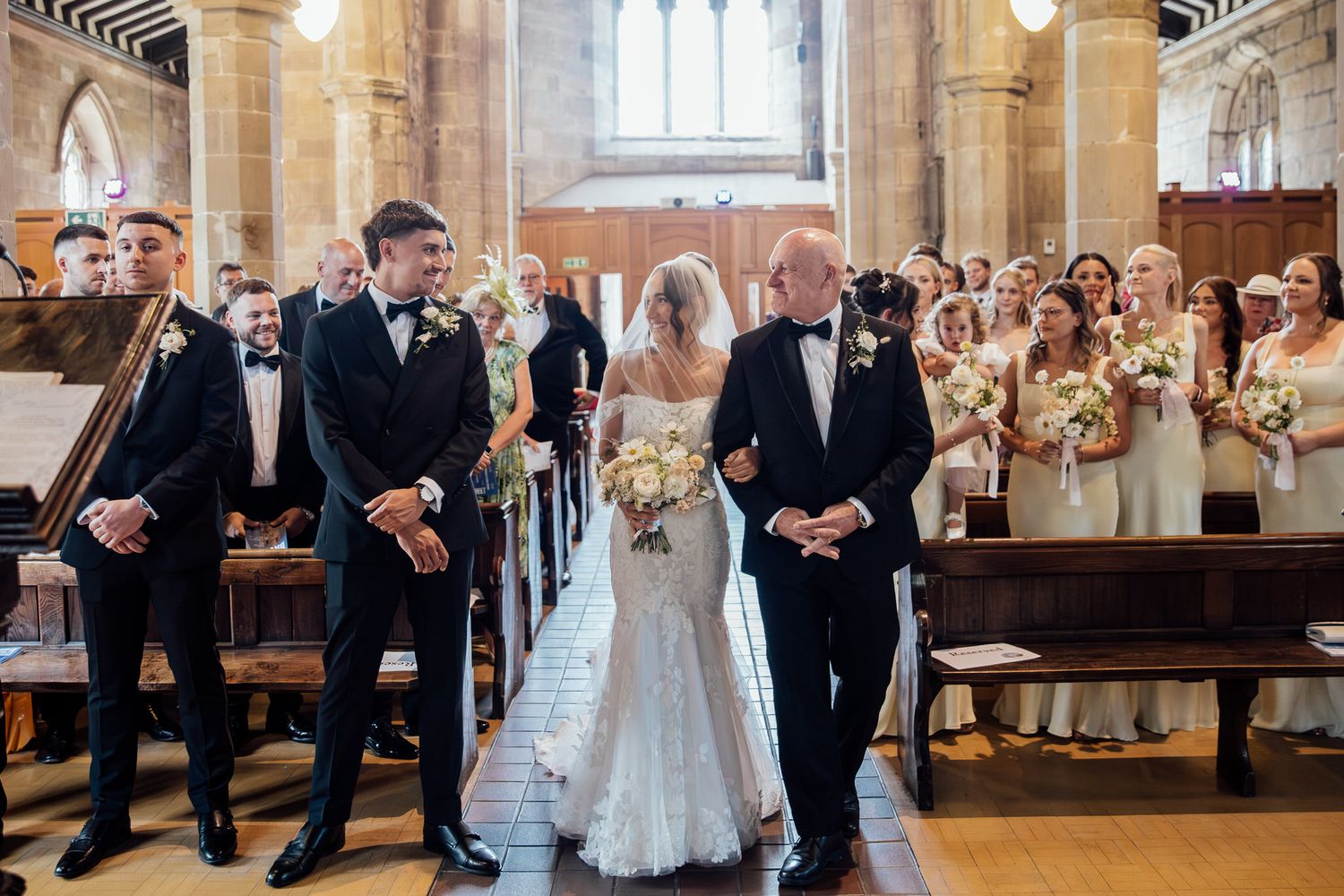 Wedding party poses together in an elegant church interior with ornate architectural details.