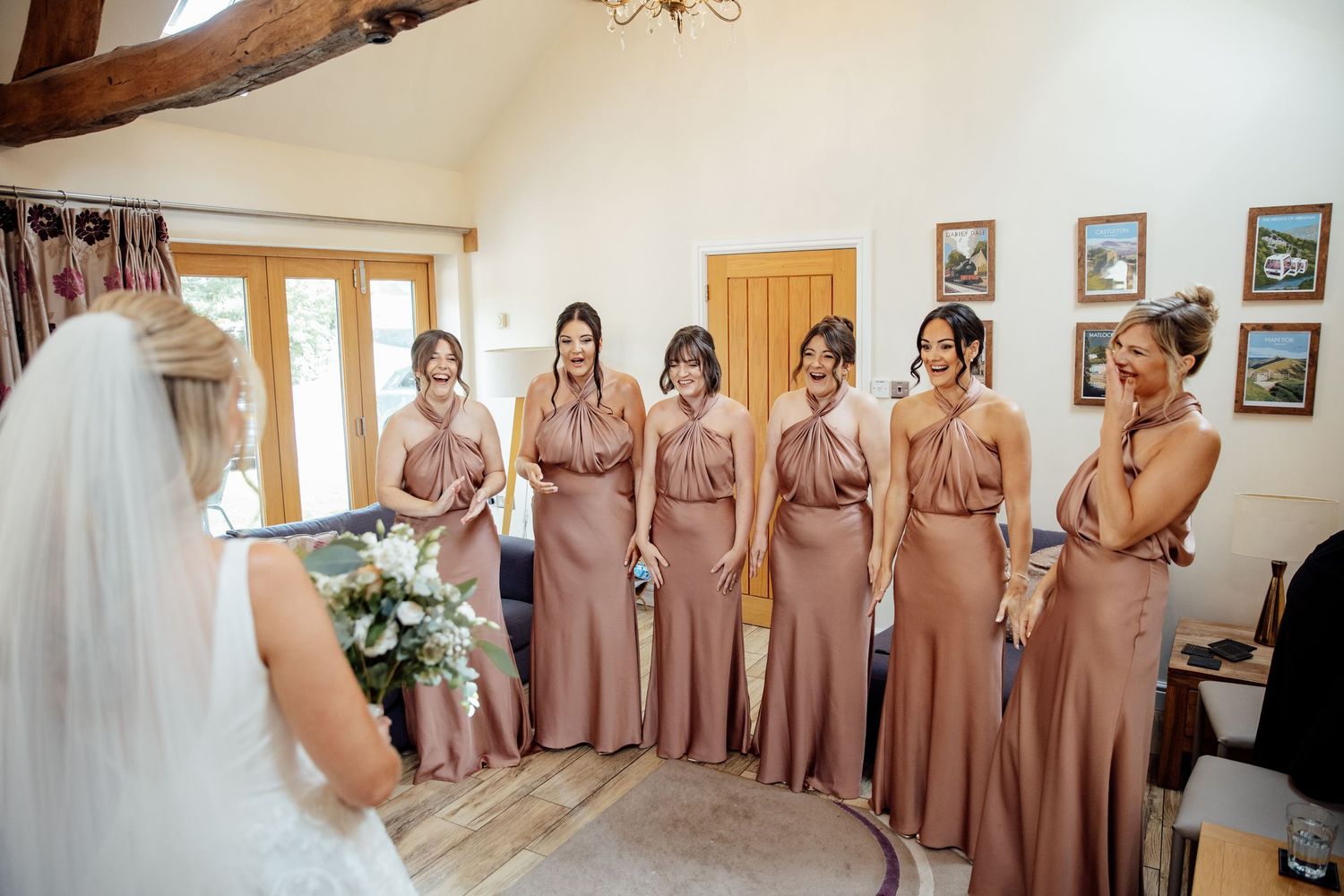 Getting ready scene with attendants in matching dusty rose dresses watching the final preparations.