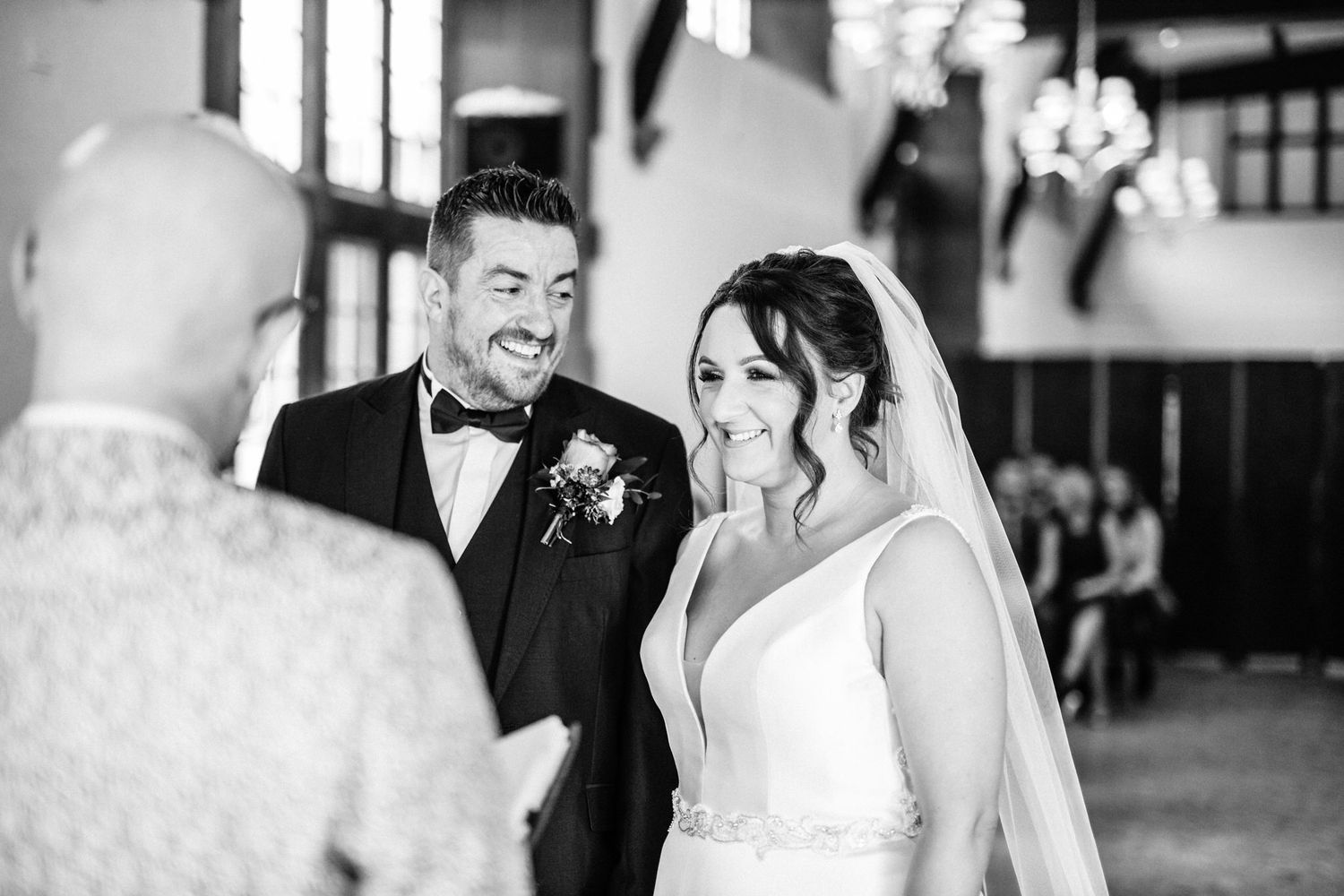 Black and white candid ceremony moment in an indoor venue with elegant decor.