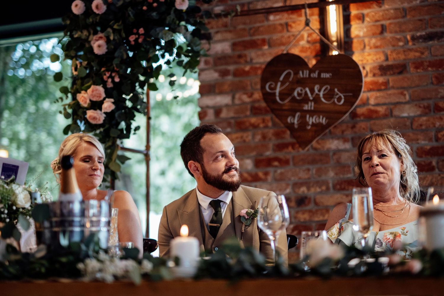 Rustic wedding reception decor with exposed brick wall and hanging lights.