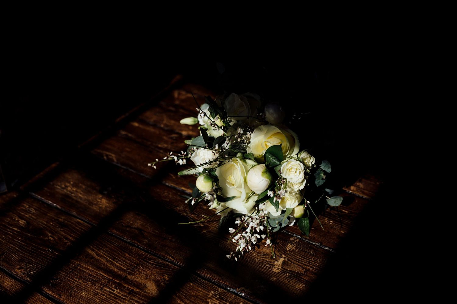 White and cream wedding bouquets arranged on a rustic wooden surface.
