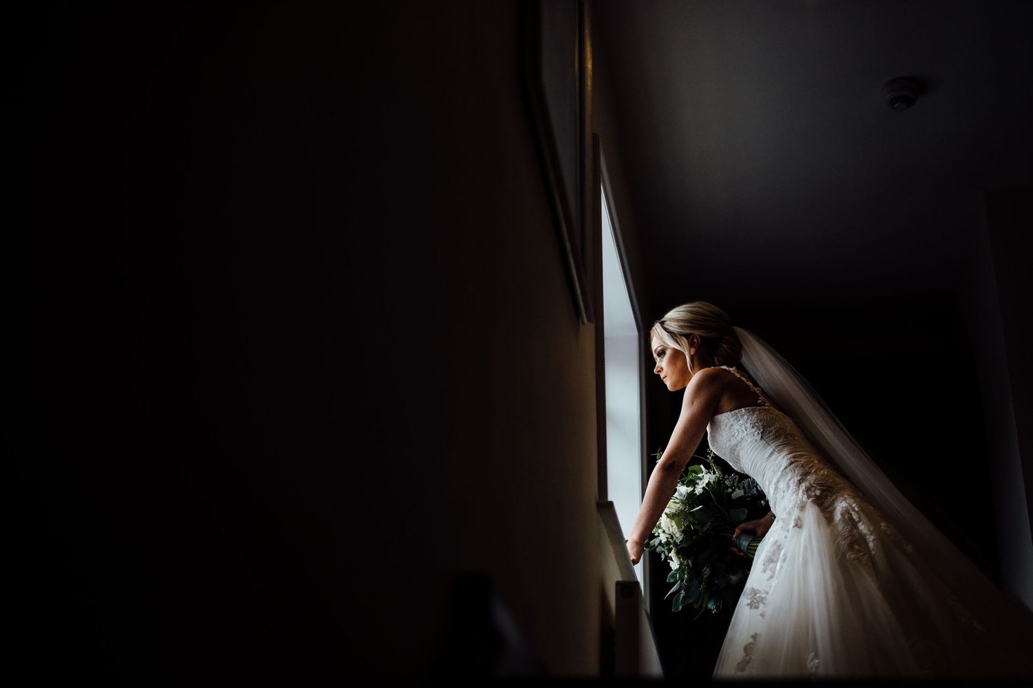 Dark atmospheric wedding photography scene with dramatic lighting and shadows.